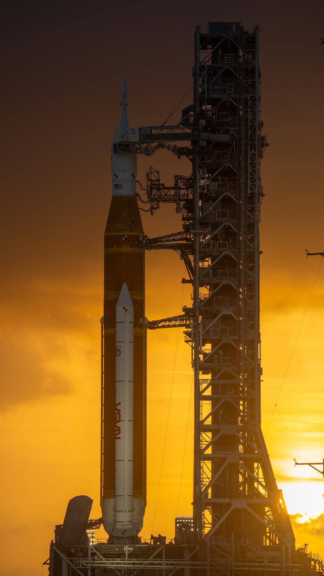 This image shows a sunset of NASA’s SLS (Space Launch System) and Orion spacecraft at NASA’s Kennedy Space Center. NASA's massive Crawler-Transporter, upgraded for the Artemis program, carried the powerful SLS rocket and Orion spacecraft on the Mobile Launcher from the Vehicle Assembly Building to Launch Pad 39B at Kennedy Space Center in preparation for the Artemis II mission.
